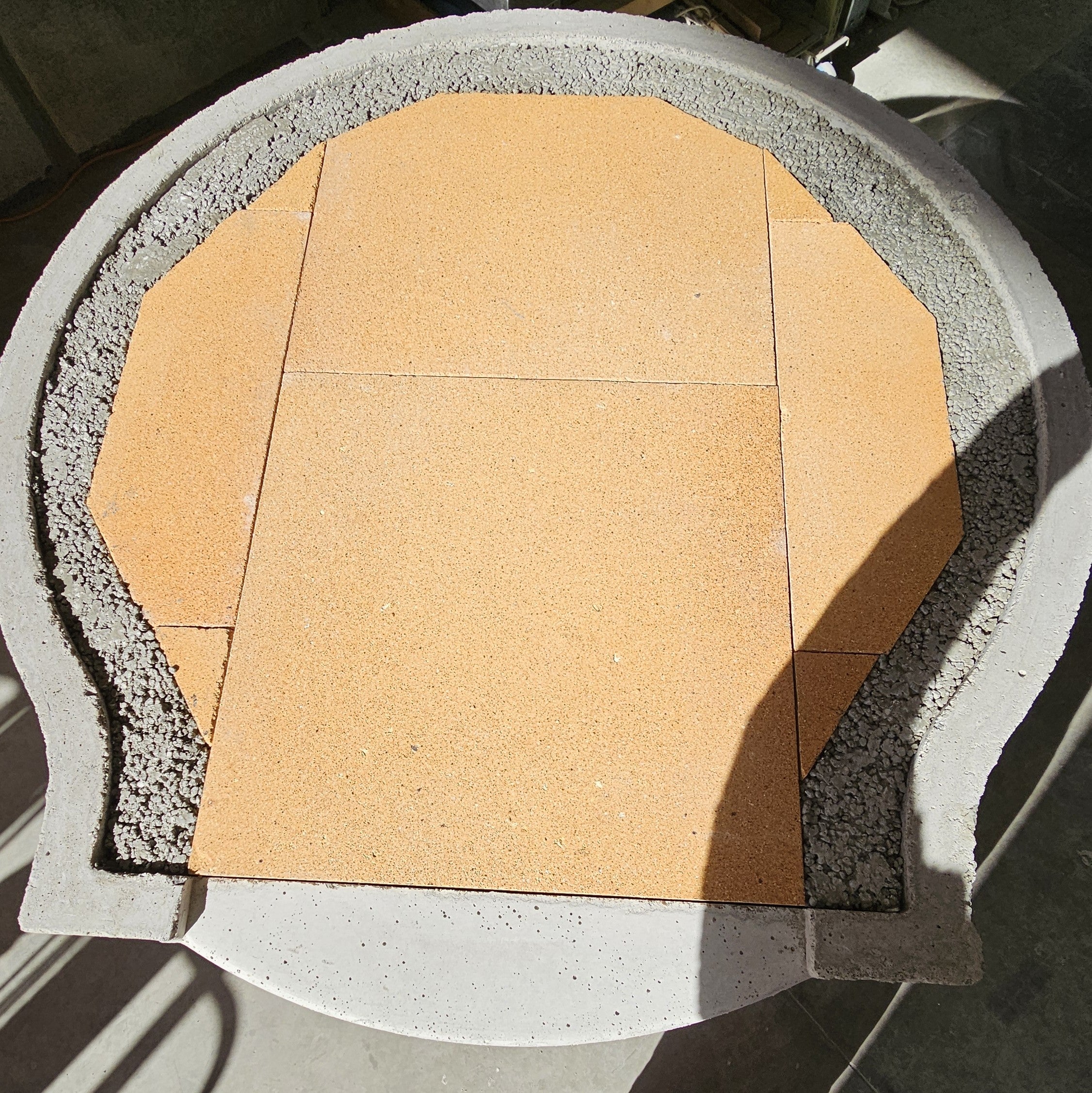 Refractory cooking floor fitted into the purpose-built Pizza Oven Club base, with the drainage layer visible around the floor.
